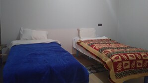 Una habitación con dos camas individuales, cada una con un edredón de color diferente.