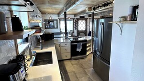 A modern kitchen with wooden ceiling beams, stainless steel appliances, and a white countertop. - Charming 3-bedroom Tabernash Tavern at Winter Park (Tabernash)