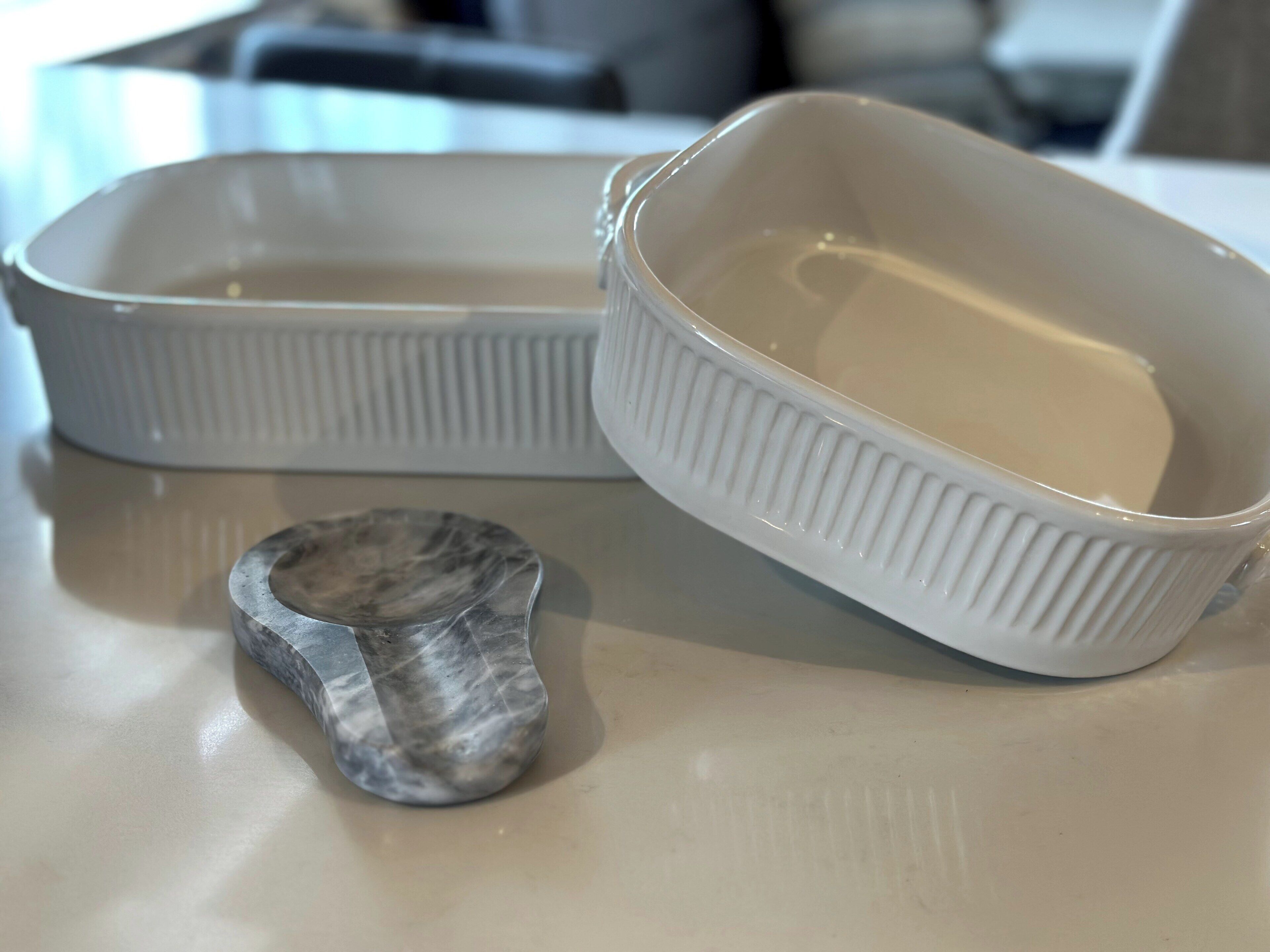 Two white ceramic dishes with ridged sides on a countertop.