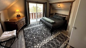 A bedroom with a bed, a dresser, a lamp, a window with curtains, and a patterned rug. - Charming 3-bedroom Tabernash Tavern at Winter Park (Tabernash)
