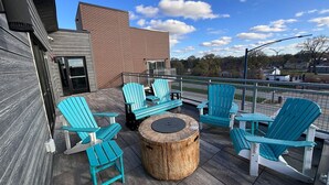 Un patio en la azotea con sillas Adirondack y una mesa de madera redonda.