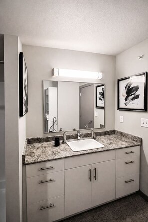 A bathroom with a double sink, a mirror, and a light fixture above the mirror.