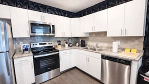 Una cocina moderna con armarios blancos, electrodomésticos de acero inoxidable y piso de madera.