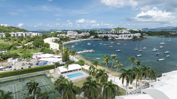 A coastal resort with multiple buildings, a marina with boats, and a tennis court. - Beachfront, Ocean Views, 2 bed, Poolside, Gym (St. Thomas)