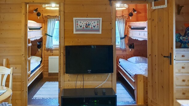 Eine Holzhütte mit Etagenbetten, einem Fernseher und einem gerahmten Bild an der Wand.