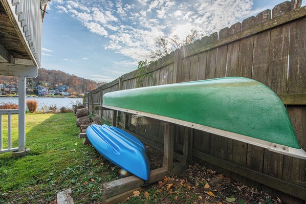 A wooden dock with two canoes, a grassy area, and a wooden fence.