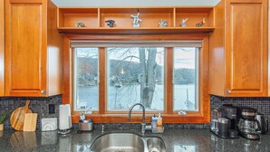 A kitchen with wooden cabinets, a double sink, a window with a view of a lake, and various kitchen appliances. - Lake Front Home w/Dock, Kayak, Canoe Right On Lake Hopatcong w/AC Wifi Huge Deck (Jefferson Township)