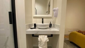 Un baño con lavamanos blanco, espejo, secador de pelo y toallero.