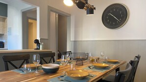 Un comedor con una mesa de madera larga, sillas y un reloj de pared.