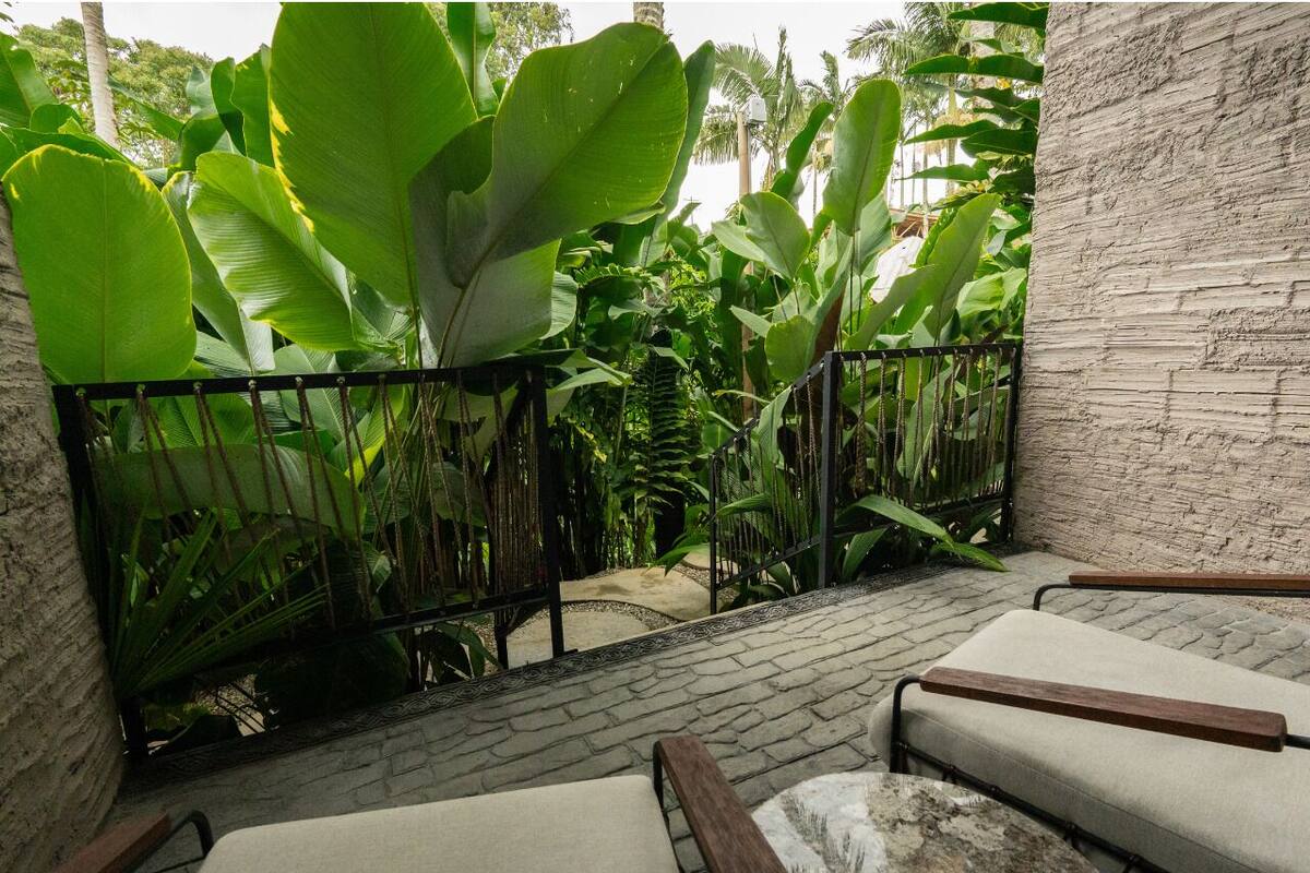 A balcony with a stone wall, a metal fence, and a bench.