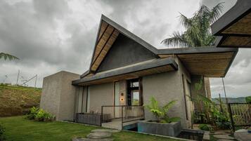Una casa moderna con techo inclinado, fachada de concreto y un pequeño porche delantero.