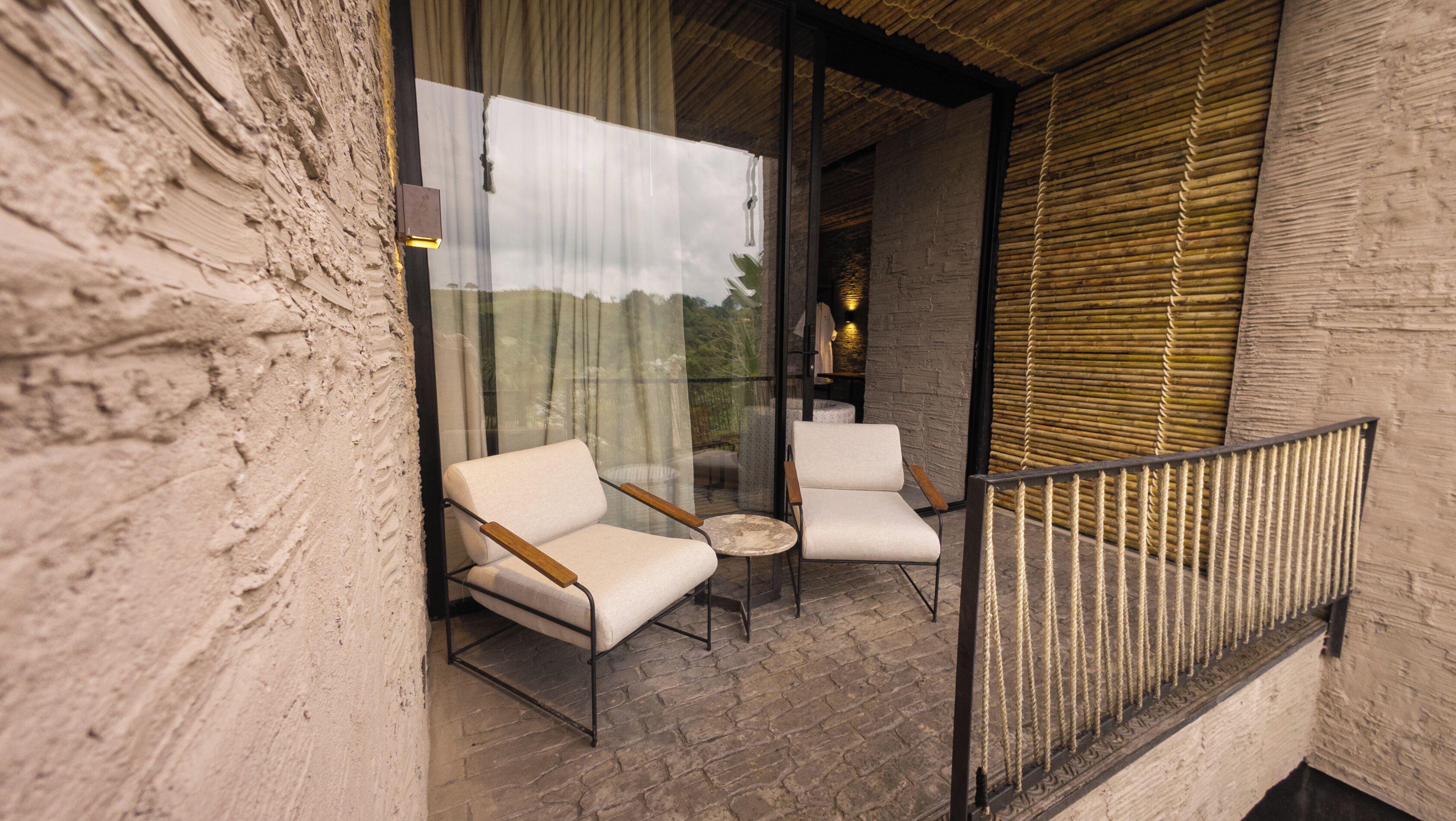 A balcony with two white armchairs, a small round table, and a glass partition.