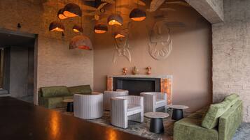 A modern lounge area with wicker furniture, a fireplace, and unique ceiling light fixtures.