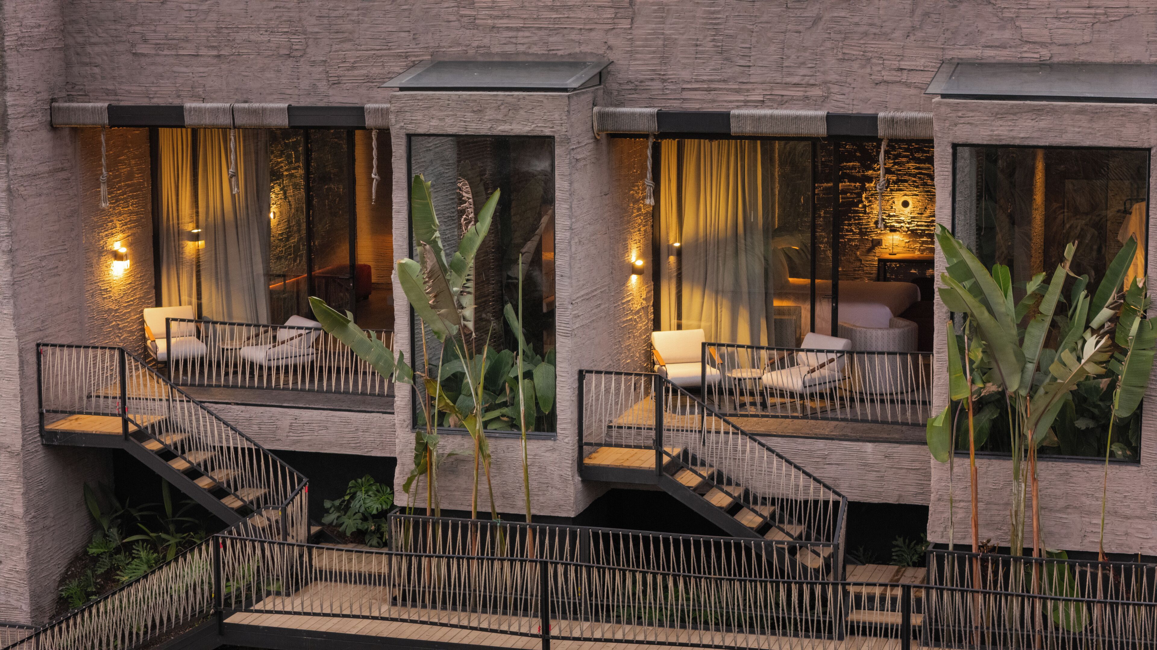 A modern building with a balcony, outdoor seating, and a staircase.