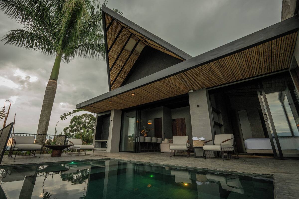 A modern house with a swimming pool, outdoor seating, and a large window overlooking the pool.