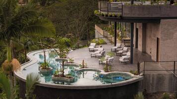 Un área de piscina con sillones reclinables y una pequeña cascada.