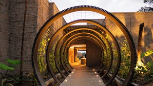 Una estructura tipo túnel con un pasillo central, paredes de ladrillo y vegetación a los lados.