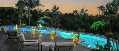 A poolside area with lounge chairs and a swimming pool surrounded by palm trees.