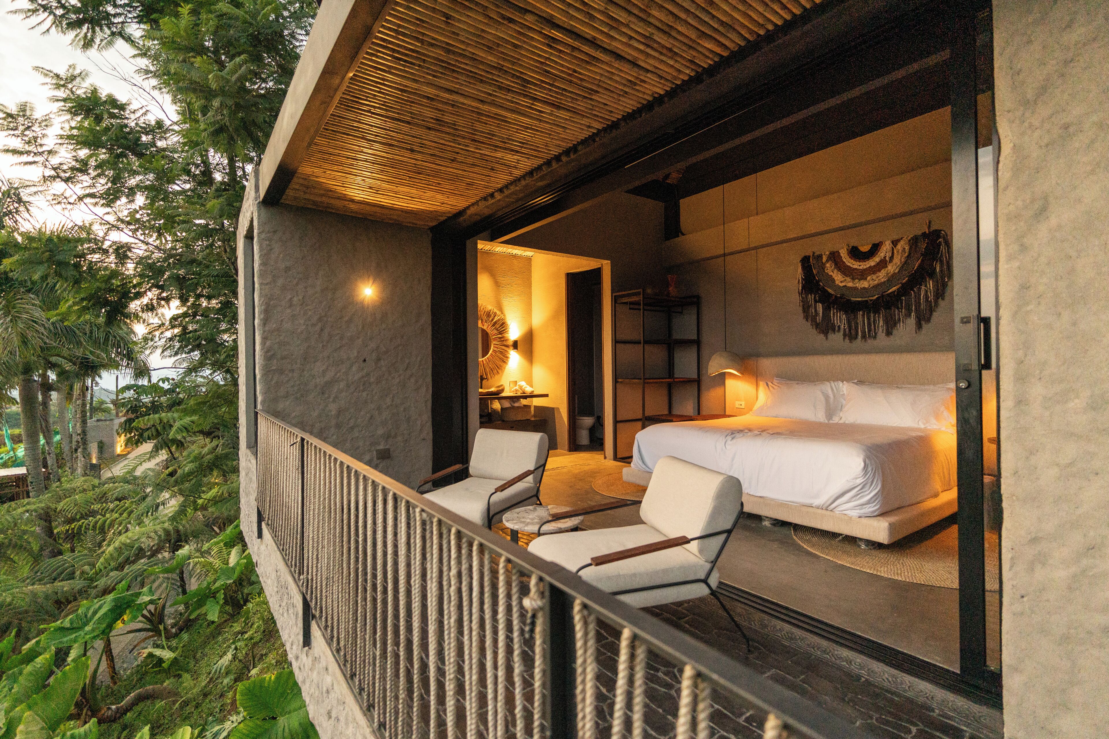 A balcony with a bed, two chairs, and a small table.