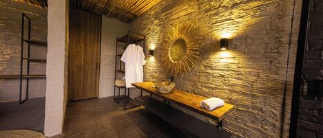 A modern bathroom with a wooden bench, a large mirror, and a towel on the bench.