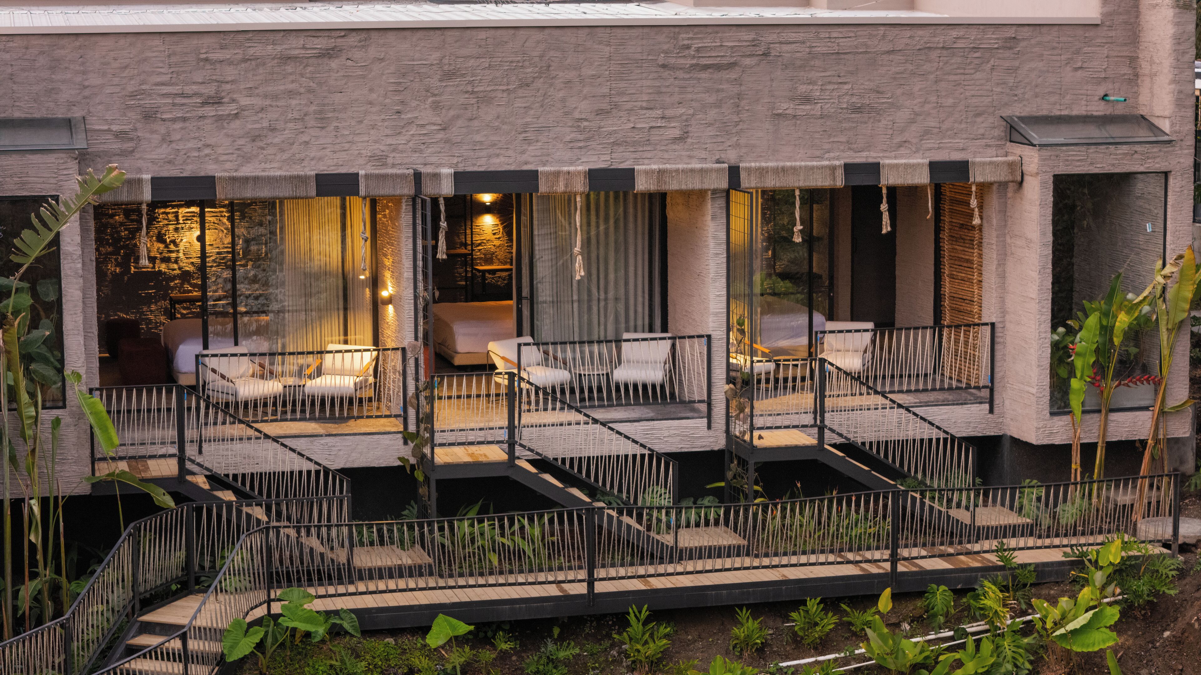 A modern outdoor patio with multiple seating areas, a staircase, and a view of the building's interior.