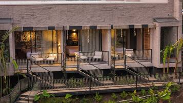 A modern outdoor patio with multiple seating areas, a staircase, and a view of the building's interior.