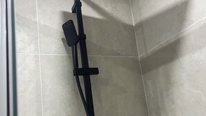 Une douche équipée d’un pommeau de douche à main fixé sur un panneau de commande mural.