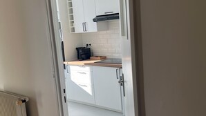 Une cuisine moderne avec des armoires blanches, une hotte noire et un plan de travail en bois.