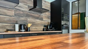 Une cuisine moderne avec un plancher en bois, des meubles de rangement noirs et une cuisinière intégrée.