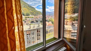 Une vue depuis une fenêtre donnant sur une ville et des montagnes.