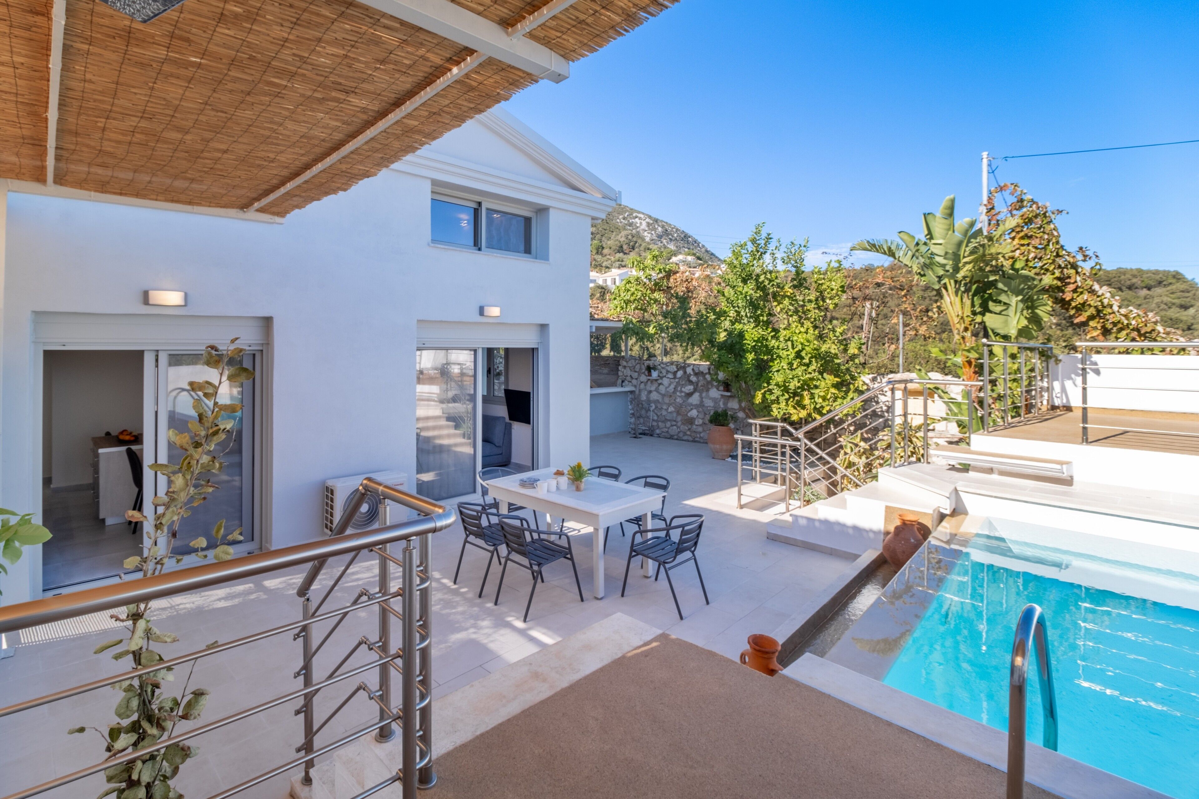 En modern villa med pool, utomhusmöbler och en vacker bergsutsikt.