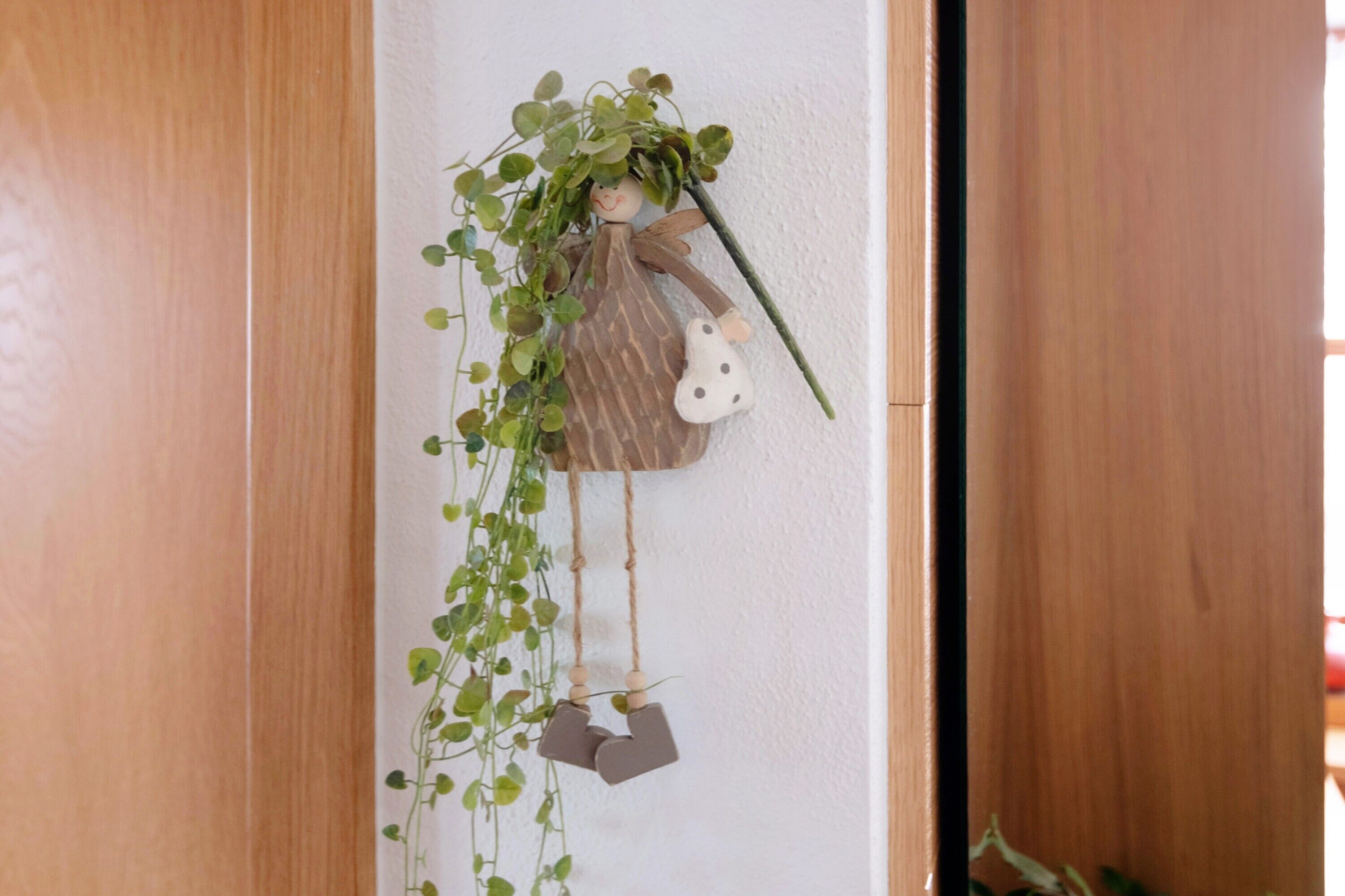 Eine Wanddekoration mit Pflanze, Figur und hängenden Elementen.