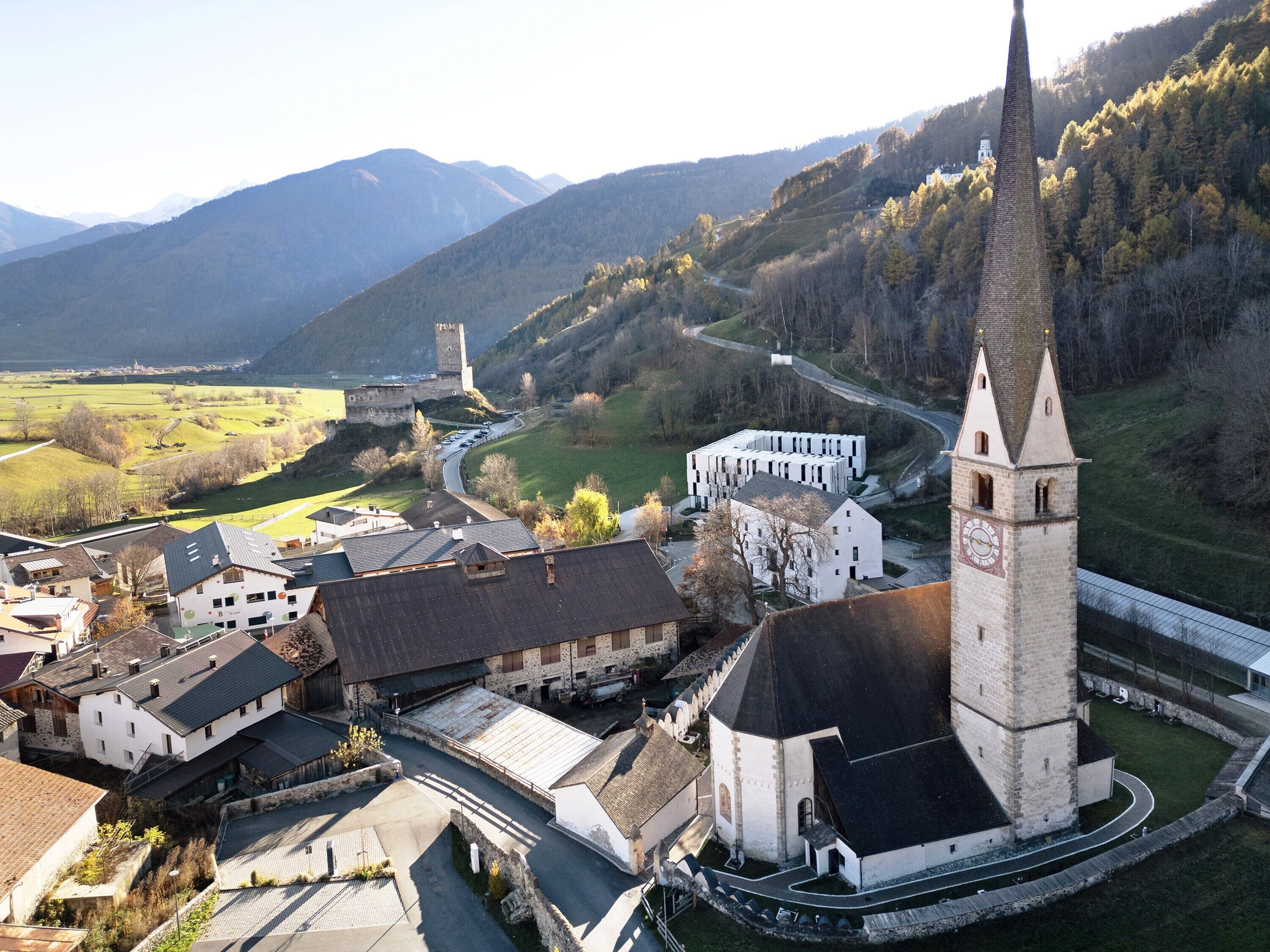 A town with a prominent church tower, a castle, and a modern building complex.