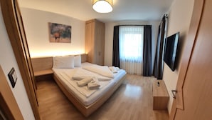 A hotel room with a bed, a bedside table, a TV, and a painting on the wall. - Apartment "Haus Peer A 2" with Mountain View, Private Terrace, and Wi-Fi (Mals)
