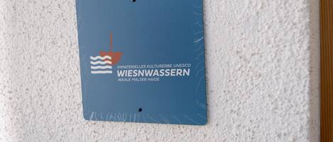 Une plaque bleue représentant un navire et des vagues, fixée sur un mur à texture.