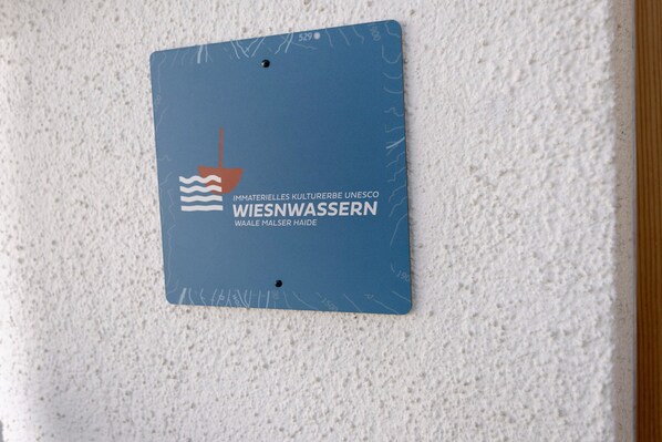 Une plaque bleue représentant un navire et des vagues, fixée sur un mur à texture.