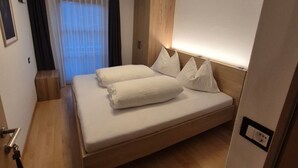 Una habitación de hotel moderna con una cama grande, cabecera de madera y una lámpara en el techo.