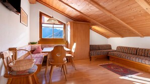 Una habitación acogedora con muebles de madera, una mesa de comedor, un sofá y una ventana con vistas a la montaña.