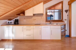 A kitchen with wooden cabinets, a built-in oven, and a window with blinds.