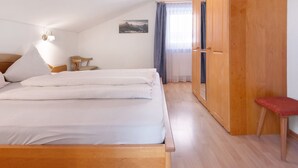 Un dormitorio con una cama, un armario de madera, una mesita y una silla.