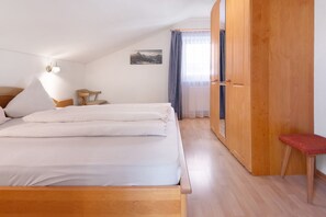 Une chambre à coucher avec un lit, une armoire en bois, une petite table et une chaise.
