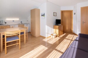 A compact living space with a kitchenette, dining area, and a sofa.