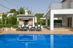 A swimming pool with lounge chairs, a covered patio, and a white building with a tiled roof. - Villa 'Angels' with Mountain Views, Wi-Fi and Air Conditioning (Teulada)