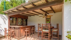 A wooden bar area with stools, a ceiling fan, and a sign. - Villa 'Rio Verde' with Sea View, Wi-Fi and Air Conditioning (Marbella)