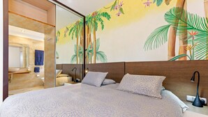 A bedroom with a large bed, a wooden headboard, a nightstand with a lamp, and a bathroom visible through a glass door. - Villa 'Rio Verde' with Sea View, Wi-Fi and Air Conditioning (Marbella)