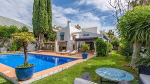 A pool with lounge chairs, a patio table, and a well-maintained garden. - Villa 'Rio Verde' with Sea View, Wi-Fi and Air Conditioning (Marbella)