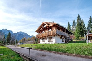 Una baita di legno con un balcone, con le montagne sullo sfondo.