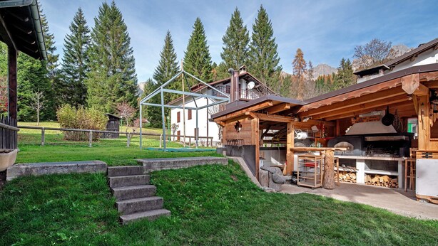 A rustic wooden building with a kitchen area, a staircase leading to a deck, and a view of a mountain range. - Apartment 'Mulaz' with Mountain View, Shared Garden and Wi-Fi (Falcade)