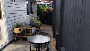 A covered patio with a round table and chairs, a sofa, and potted plants.