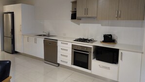 A modern kitchen with stainless steel appliances, wooden cabinets, and a tiled floor.